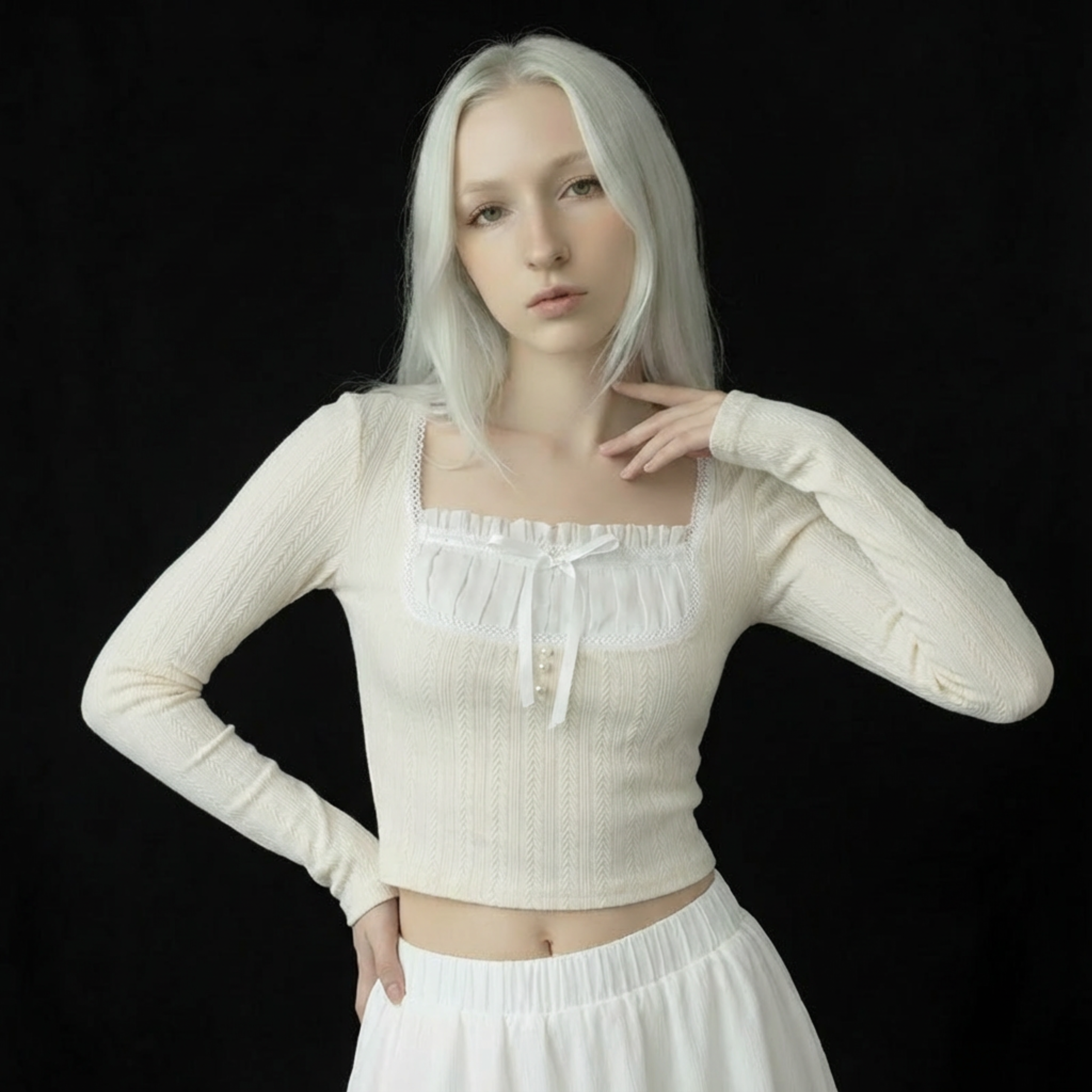 Woman wearing a white long-sleeve top and skirt against a black background